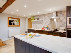 A modern kitchen with a marble island, wooden cabinets, and patterned backsplash. - 3 Bed in Ventnor (oc-93697) (Niton)