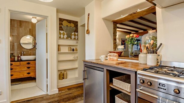 Une cuisine moderne dotée d’un four encastré, d’un plan de travail en bois et d’un revêtement mural à motifs géométriques.