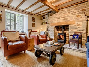 A cozy living room with leather sofas, a coffee table, and a stone fireplace.