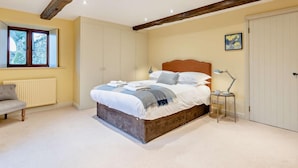 A bedroom with a bed, bedside table, lamp, radiator, window, and a door. - 3 Bed in Penrith (oc-93379) (Orton)