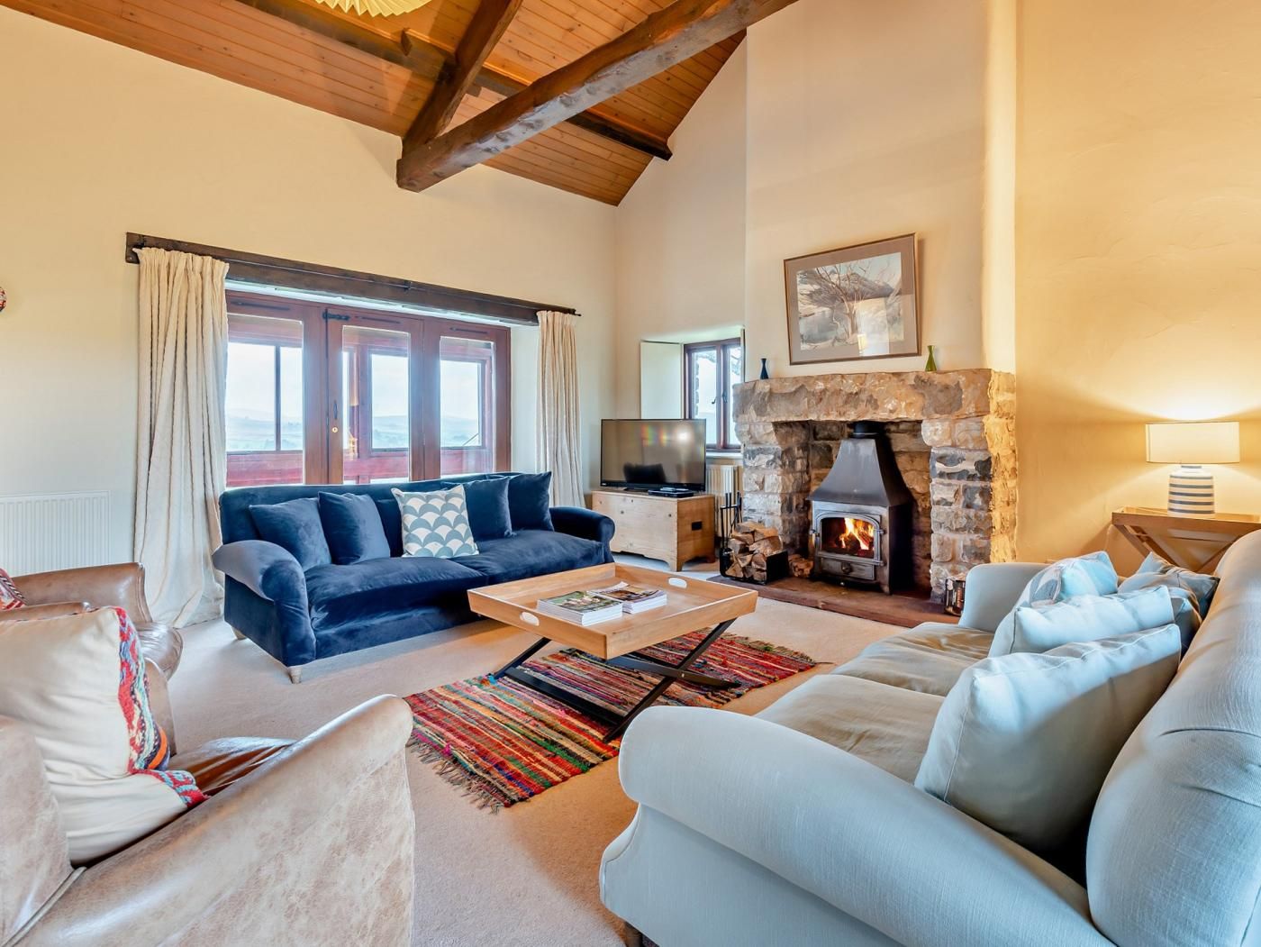 A cozy living room with a stone fireplace, a blue sofa, and a television.