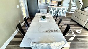 Une cuisine moderne avec un plan de travail en marbre, des chaises en osier et une table à manger.