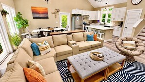 Un vaste espace de vie comprenant un canapé, un pouf et une table à manger.