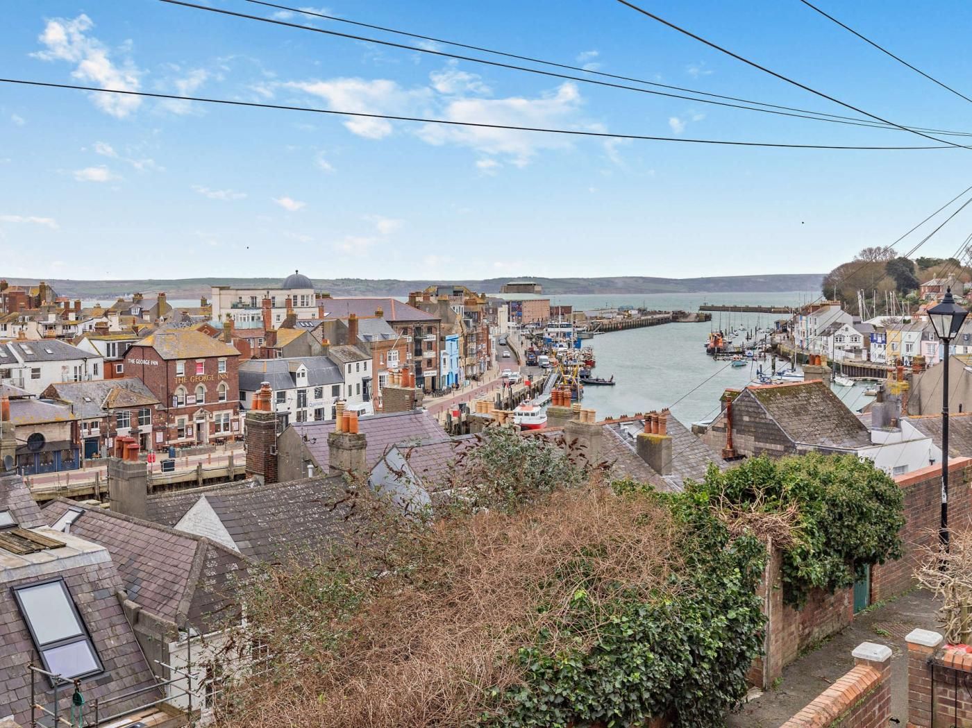 A coastal town with a river, buildings, and a dock with boats.