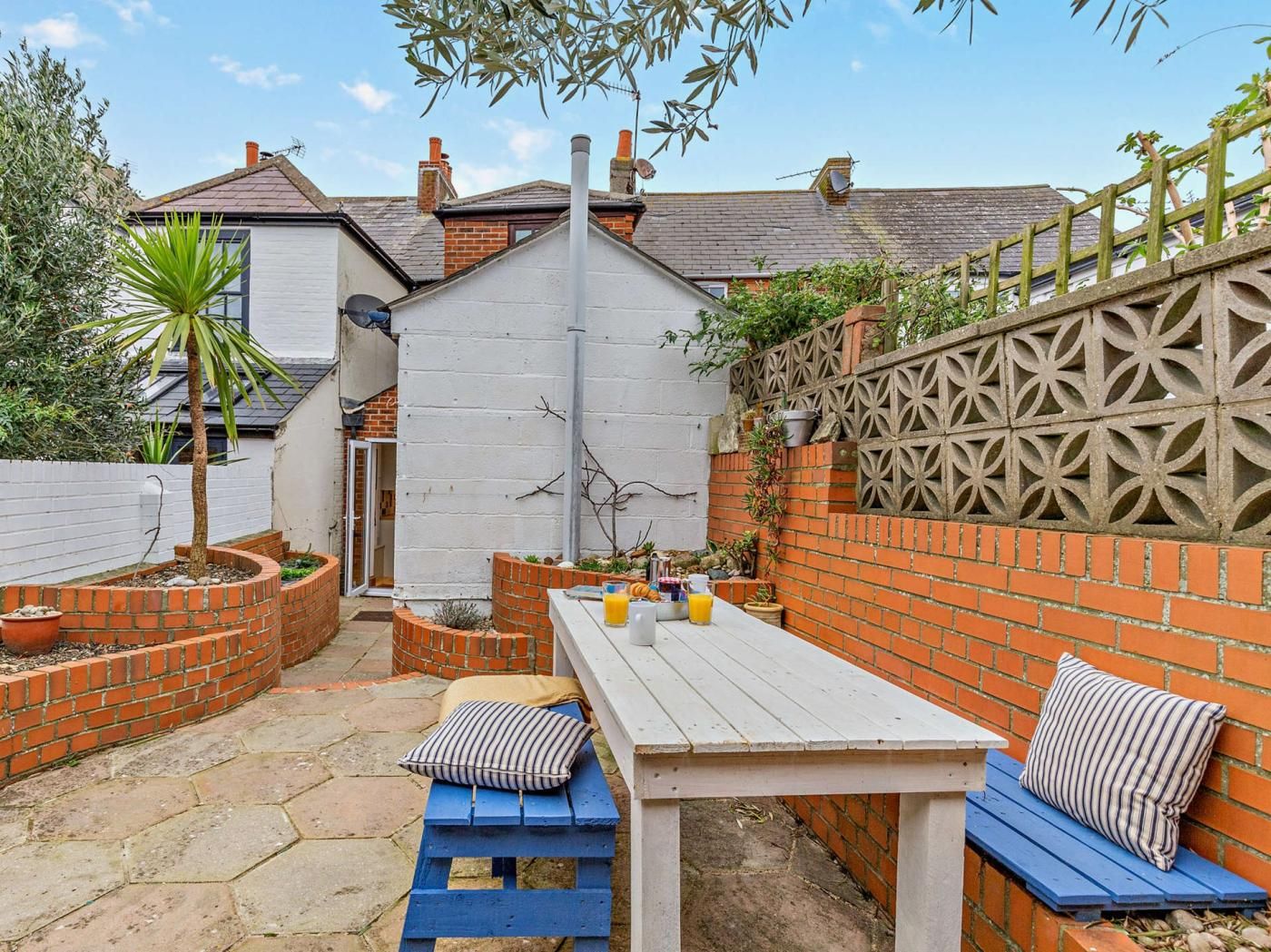 A patio area with a table and benches, surrounded by brick walls and a decorative fence.