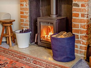 A wood-burning stove, a white bucket, and a blue basket with logs. - 2 Bed in Weymouth (oc-94093) (Weymouth)