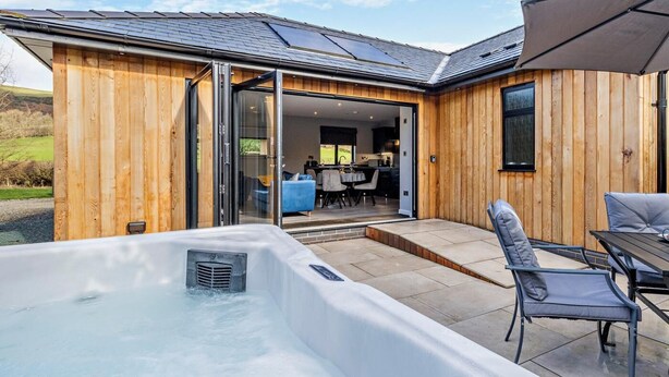Ein Holzhaus mit Whirlpool, einem Essbereich und einer durchgehenden Tür erkennbaren Küche.
