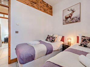 A bedroom with two beds, a wooden ceiling, a painting of a deer, and a nightstand with a lamp. - 2 Bed in New Quay (oc-94160) (New Quay)