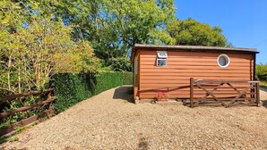 A small wooden building with a gravel driveway, a wooden gate, and a hedge. - 1 Bed in East Cowes (oc-91562) (Whippingham)