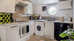 A compact kitchen with a washing machine, dishwasher, and a small window. - 1 Bed in East Cowes (oc-91562) (Whippingham)
