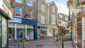 A narrow street lined with shops, including a stationery store and a bakery. - 1 Bed in East Cowes (oc-91562) (Whippingham)