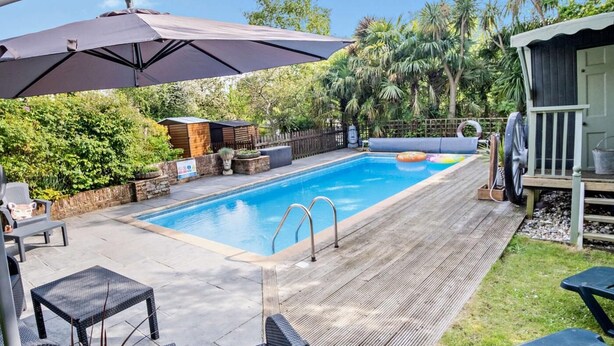 Une piscine avec une terrasse en bois, des chaises longues et un parasol.