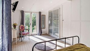 Une chambre à coucher avec un lit, une chaise, un bureau et une grande fenêtre.