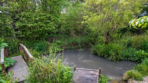 Un pont en bois enjambant un étroit canal, entouré d’une végétation luxuriante.