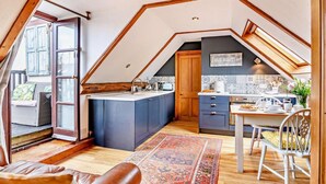 Eine Loft-Küche mit Kochinsel, Holzbalken und Blick ins Freie.