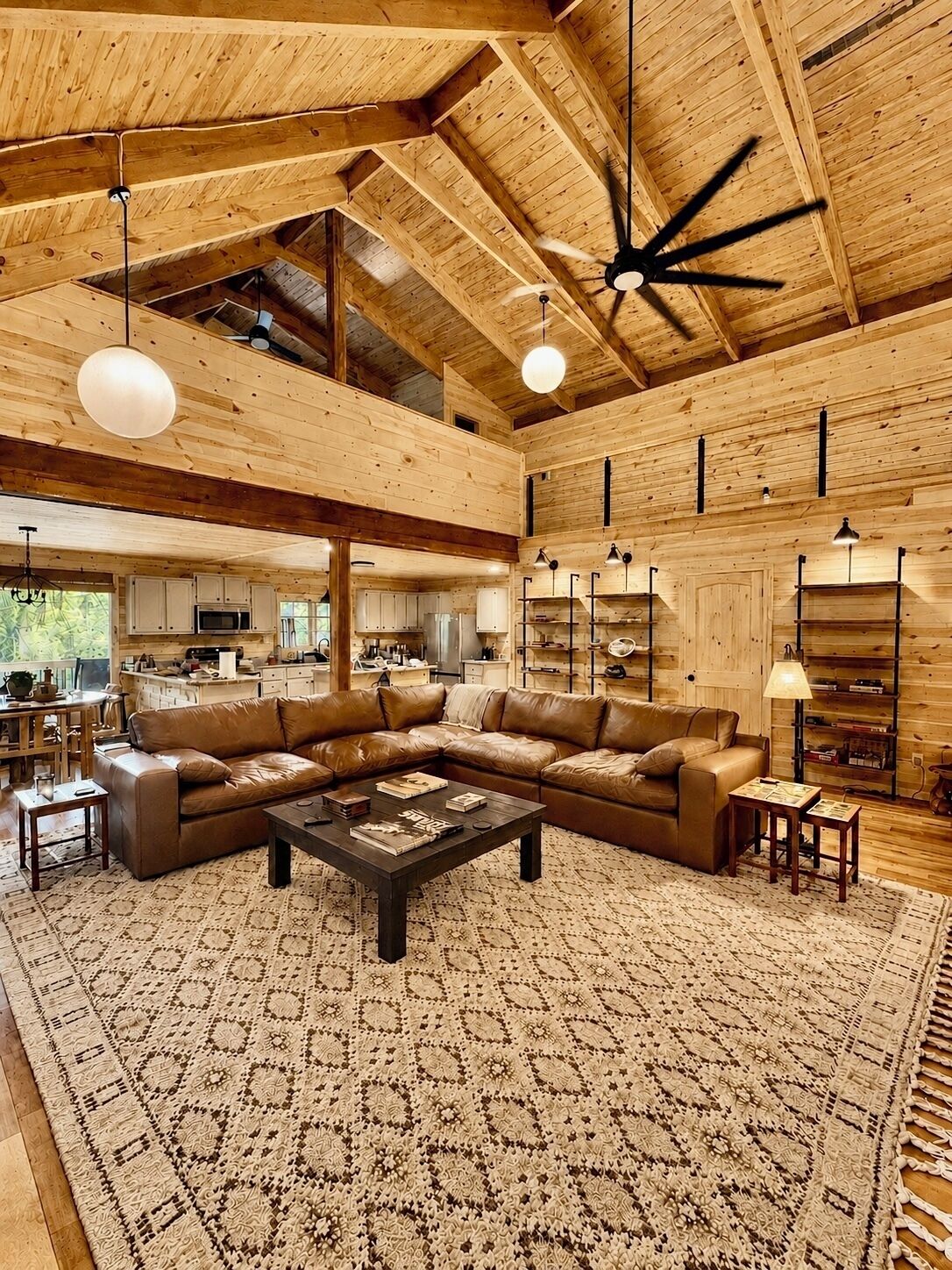 A spacious living area with a large L-shaped leather sofa, a coffee table, and a patterned rug.
