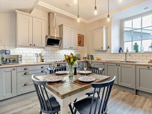 Una cocina moderna con armarios blancos, una mesa de comedor de madera y un ventanal grande.