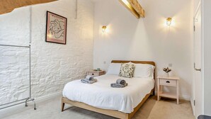 Ein Schlafzimmer mit einem hölzernen Bett, weißen Wänden, einer weißen Decke und zwei Nachttischen mit Lampen.