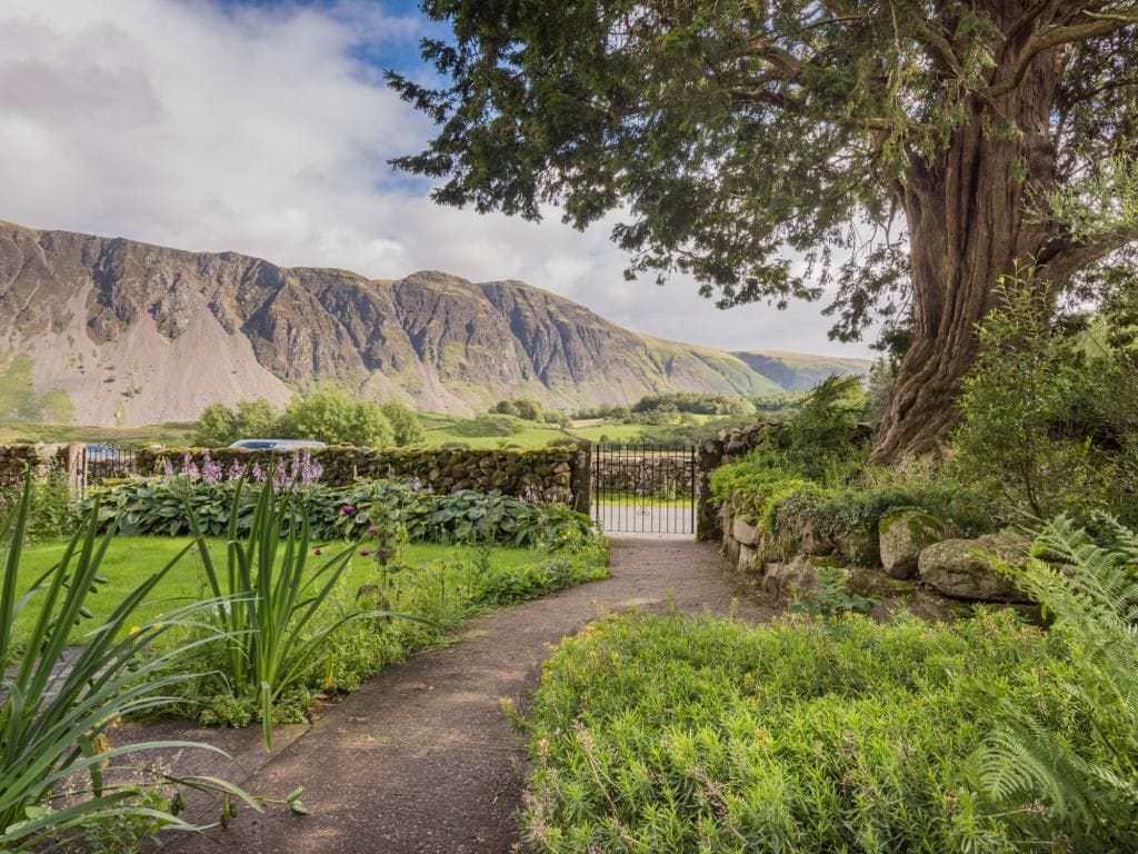 A pathway leading to a gate with a mountainous backdrop.