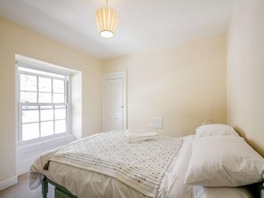 Ein Schlafzimmer mit großem Fenster, einem Bett mit weißer Bettwäsche und einer hängenden Deckenleuchte.