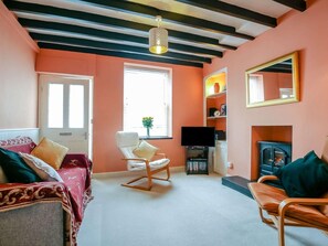 A living room with a sofa, a chair, a TV, and a fireplace. - 1 Bed in Aberdovey (oc-87910) (Aberdovey)