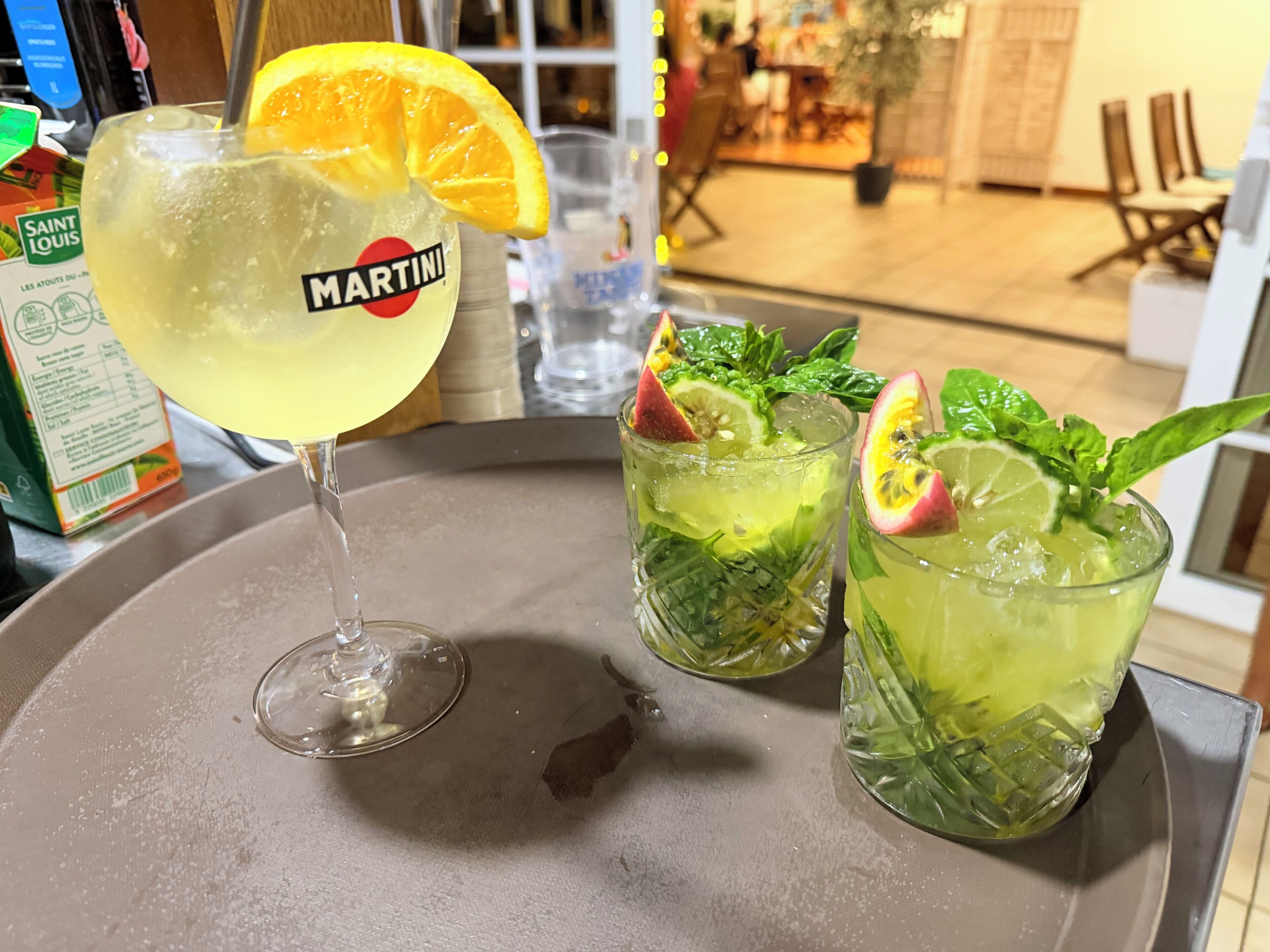 A martini glass with a lemon slice and a bottle of Martini, and two glasses with a lime and mint garnish.