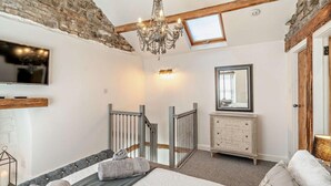 Un dormitorio con cama, candelabro, televisor, espejo y una escalera.
