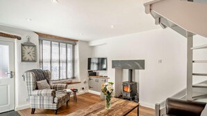 Una sala de estar con sofá, mesa de centro, chimenea, televisor y un reloj en la pared.