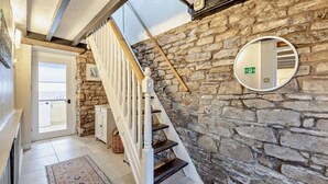 Eine Treppe mit weißen Balustraden, eine Steinmauer, ein runder Spiegel und ein Teppich.