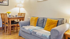 Ein gemütliches Wohnzimmer mit einer Couch, einem Esstisch mit Stühlen und einer Lampe.