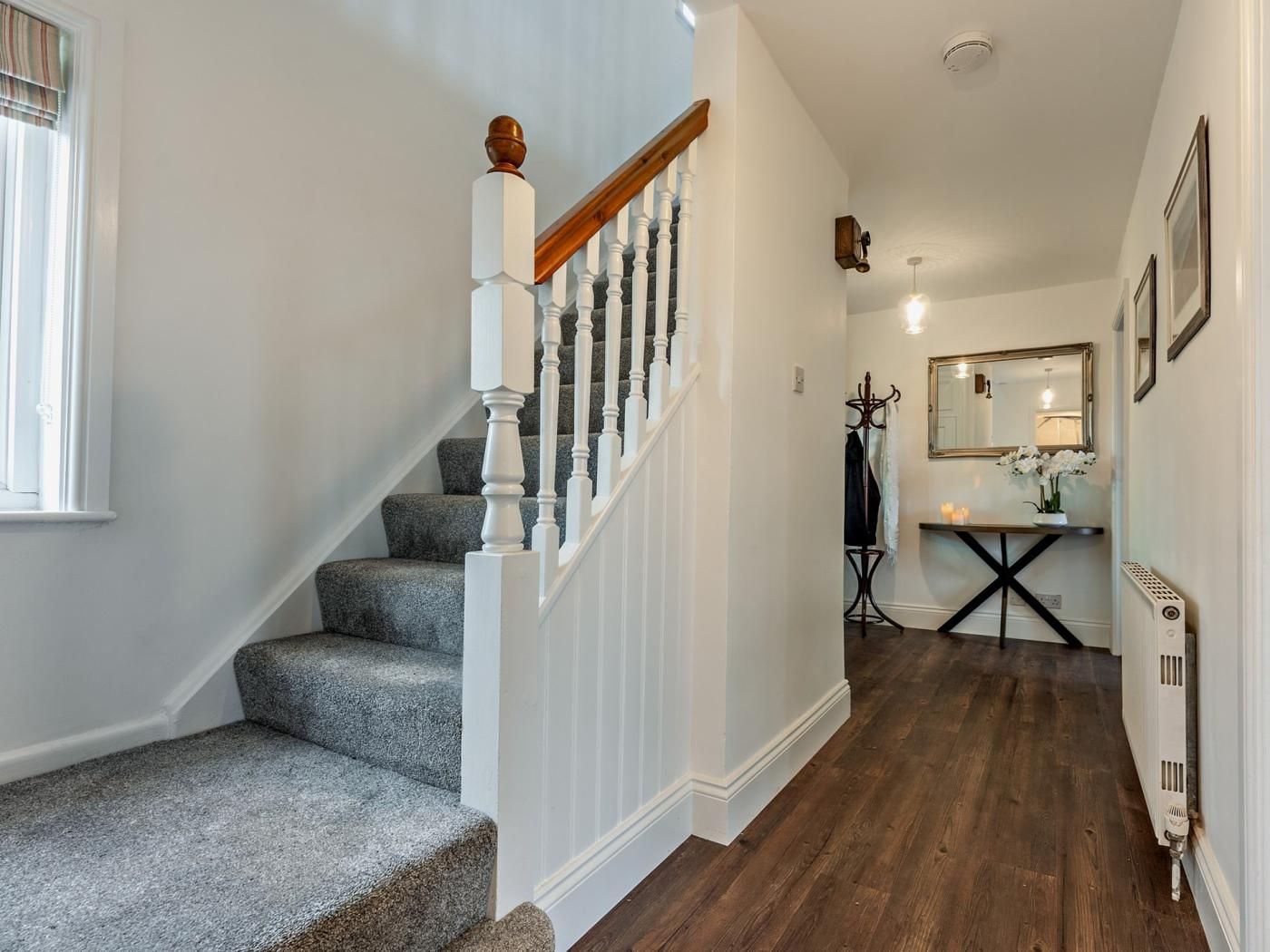 Un escalier avec une rampe en bois et des balustrades blanches menant à un palier.
