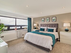 Una camera da letto con un letto grande, due comodini, una finestra con vista e tre quadri appesi al muro.