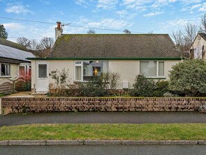A single-story house with a sloped roof, a brick wall in front, and a paved driveway. - 1 Bed in Keswick (oc-94245) (Keswick)