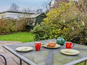 A metal table with plates, cutlery, and red cups in a garden setting. - 1 Bed in Keswick (oc-94245) (Keswick)