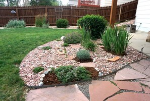 A landscaped garden with a stone pathway, various shrubs, and a wooden fence in the background. - Perfect Vacation Haven for the Active and Musical Family (Superior)