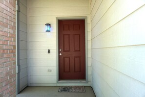 A door with a light fixture above it, a doormat, and a brick wall to the left. - Perfect Vacation Haven for the Active and Musical Family (Superior)