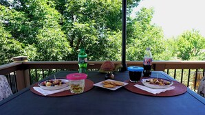 Un tavolo con cibo e bevande su un balcone sullo sfondo di alberi.