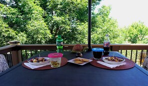 Ein Tisch mit Speisen und Getränken auf einem Balkon, im Hintergrund Bäume.