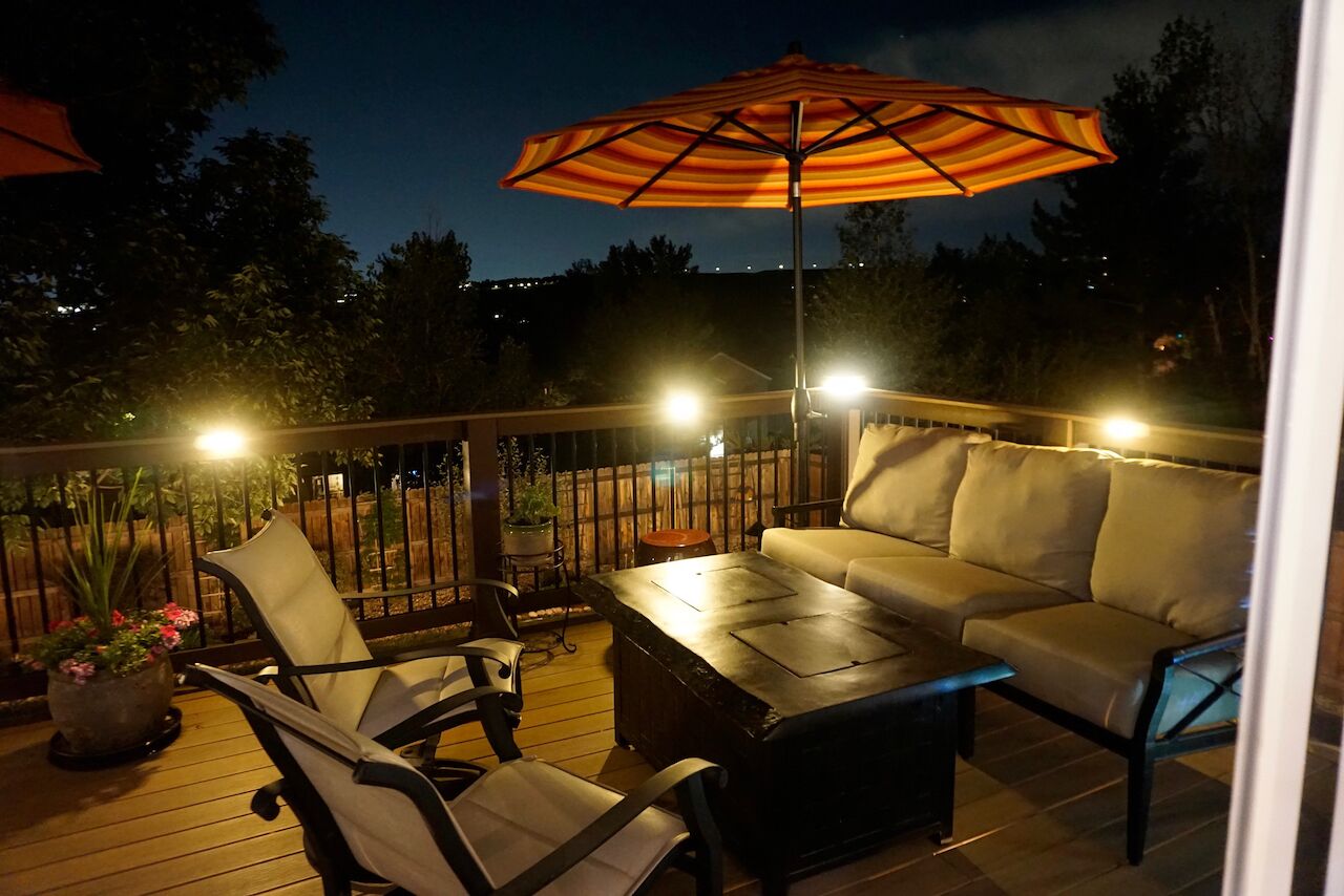 Una terraza al aire libre con un sofá, sillas, una mesa y una sombrilla.