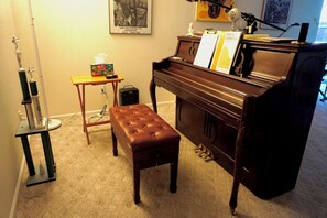 A piano with sheet music, a bench, and a small table with a box and a tissue box. - Perfect Vacation Haven for the Active and Musical Family (Superior)
