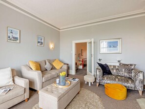 Ein Wohnzimmer mit zwei Sofas, einem Couchtisch und einem gemusterten Sofa.