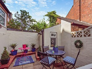 A small patio area with a round table and chairs, potted plants, and a red chair. - 2 Bed in Lytham St. Annes (oc-94212) (Saint Anne's on the Sea)