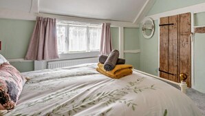 A bedroom with a bed, a window with curtains, a wooden door, and a ceiling light fixture. - 2 Bed in Hastings (oc-94200) (Pett)