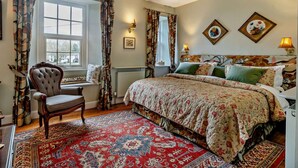 Ein Schlafzimmer mit einem großen Bett, einem Sessel, einem Fenster und einer Heizung.