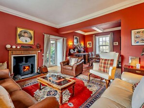 A living room with a fireplace, leather sofas, a coffee table, and a red carpet. - 4 Bed in Penrith (oc-94247) (Greystoke)