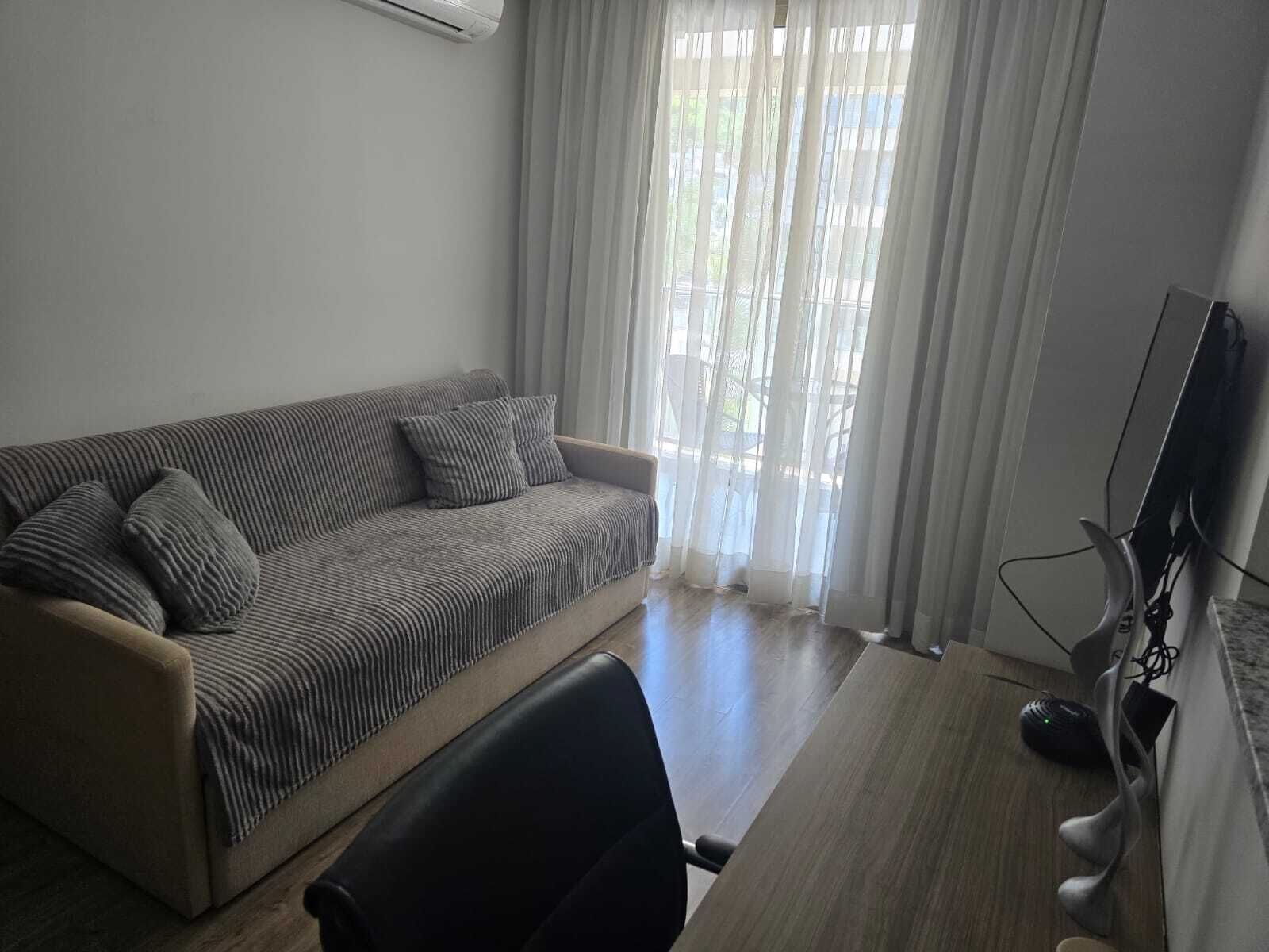 A living room with a sofa, a TV, and a desk.