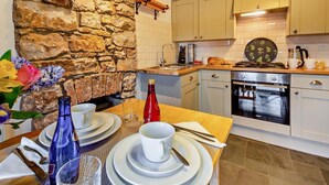 A modern kitchen with a stone wall, wooden countertop, and white cabinets. - 1 Bed in Caernarfon (oc-93802) (Caernarfon)