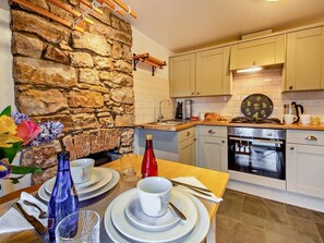 A modern kitchen with a stone wall, wooden countertop, and white cabinets. - 1 Bed in Caernarfon (oc-93802) (Caernarfon)