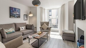 Un salon moderne comprenant un canapé, un fauteuil, une table basse et un téléviseur.