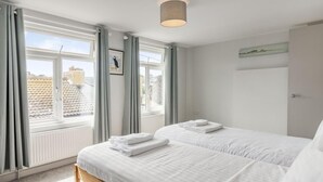 Une chambre avec deux lits, une fenêtre avec des rideaux, un luminaire au plafond et une porte.